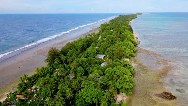 MARSHALL ISLANDS - 3.18.2024 - Excellent aerial footage moving along a beach lined with greenery and palm trees and waves lap the shore in the Marshall Islands.