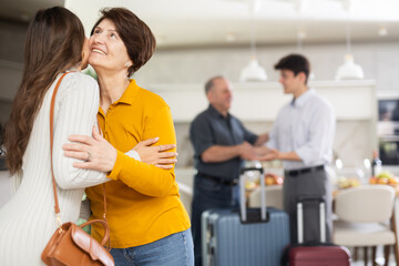 Hospitable friendly elderly woman warmly greeting and kissing daughter-in-law coming for cozy...