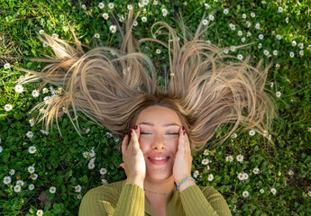 To view charismatic girl laughing with her eyes closed laying on the grass, hair model 