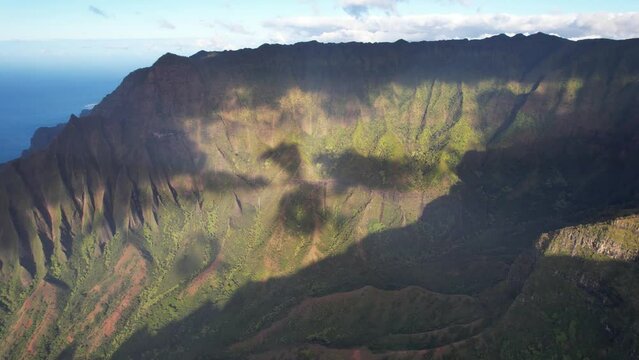 KAUAI - 3.19.2024 - Excellent aerial view circling partially sunlit mountains on the Napali Coast mountains of Kauai, Hawaii.