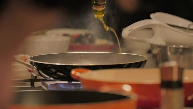  Cheff poors oil over a frying pan at a professional kitchen