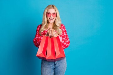Portrait of satisfied nice person dressed knitwear jumper in pink sunglass show you shopping bags...