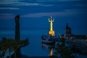 Die golden schimmernde Imperia-Statue thront in der Morgendämmerung über dem Hafen. Konstanz,...