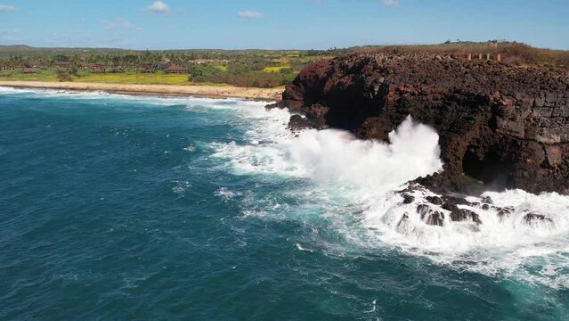 MOLOKAI - 3.19.2024 - Excellent aerial view of waves crashing against a rocky cliff on a beach of Molokai, Hawaii in slow motion.