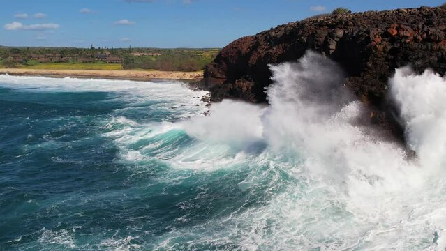 MOLOKAI - 3.19.2024 - Excellent aerial footage approaching the rocky shore of Molokai, Hawaii as waves crash against it in slow-motion.