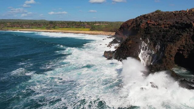 MOLOKAI - 3.19.2024 - Great aerial footage approaching the rocky shore of Molokai, Hawaii as waves crash against it in slow-motion.