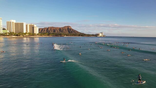 WAIKIKI - 3.19.2024 - Great aerial view circling surfers riding waves rolling towards Waikiki, Hawaii.