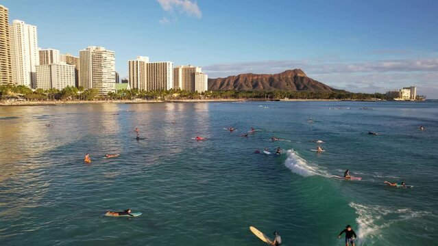 WAIKIKI - 3.19.2024 - Fantastic aerial view of surfers riding waves rolling towards Waikiki, Hawaii.
