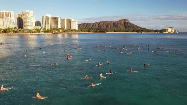 WAIKIKI - 3.19.2024 - Very good aerial view of surfers sitting on their boards while others paddle out towards them off the coast of Waikiki, Hawaii.