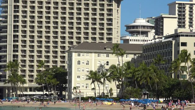 WAIKIKI - 3.19.2024 - Tourists enjoy a palm tree-lined beach in Waikiki, Hawaii.