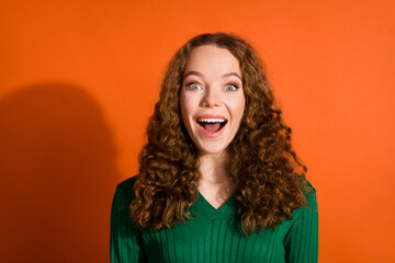 Photo of impressed excited lady dressed green shirt smiling open mouth emtpy space isolated orange color background