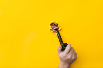 The hand of a young man holds a smoking pipe on a background of yellow paper. Mouth and lips in a...
