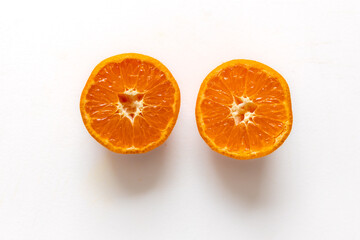 juicy orange tangerine cut in half with white background.