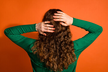 Photo of lady dressed green shirt standing back washing arms wavy hair isolated orange color background
