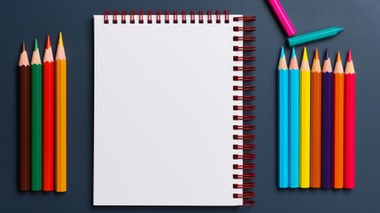 Colored pencils and a notebook on gray background