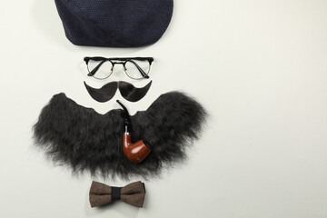 Flat lay composition with artificial moustache and glasses on light grey background, space for text