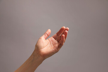 Woman holding something in hand on grey background, closeup