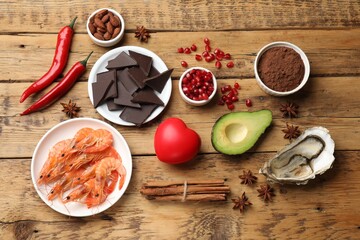 Natural aphrodisiac. Different food products and heart model on wooden table, flat lay