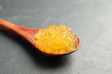 Fresh pike caviar in spoon on black table, closeup