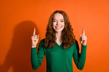 Photo of excited funky lady dressed green shirt pointing two fingers up emtpy space isolated orange color background