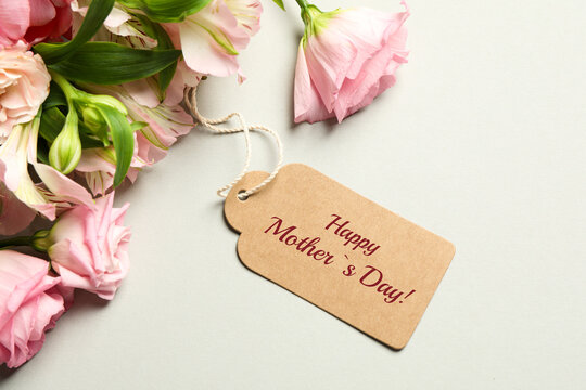 Happy Mother's Day greeting label and beautiful flowers on beige background