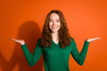 Photo of sweet shiny lady dressed green shirt compating two arms emtpy space isolated orange color background