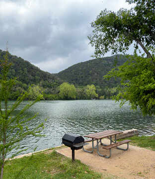 Inviting picnic table slab with BBQ on the Colorado River in Austin Texas with Texas Hill Country on the opposite shore.