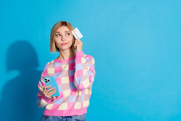 Photo portrait of pretty young girl hold gadget credit card look empty space wear trendy pink outfit isolated on blue color background