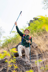 active senior man in hiking clothes,standing on the hill,freedom emotion,right hand holding trekking pole raising up,concept of elderly people lifestyle activity,active,adventure,exploring in nature