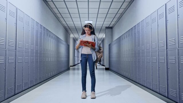 Full Body Of Asian Teen Girl Student With A Backpack Wearing Headphones And Taking Note On Notebook While Standing in Corridor