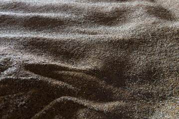 A sandy beach with a lot of sand. The sand is spread out in a way that it looks like a wave