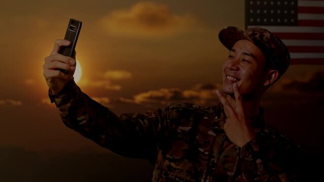 Close Up Of Asian Man Soldier Using Smartphone Taking Picture While Standing With Flag Of The United States, Sunset Time