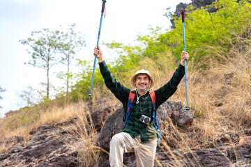 active senior man in hiking clothes,standing on the hill,freedom emotion,right hands holding trekking poles raising up,concept of elderly people lifestyle activity,active,adventure,exploring in nature