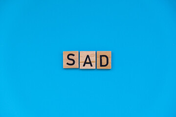 Seasonal affective disorder - text of wooden blocks on blue bright background. Concept of depression mood stress and anxiety. SAD