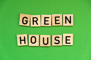 Green house text on wooden blocks on green background. Ecological concept Sustainable responsible living. Copy space