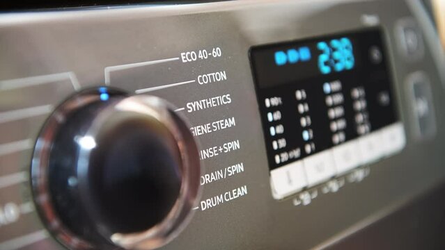 A ecology, energy saving concept with a person turning on the washing machine in the eco wash setting and pressing the button to start the wash cycle.