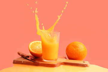 Glass of fresh orange juice with splashes on red background