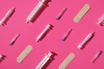 Needles, syringes and plasters on pink background