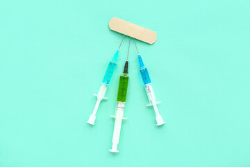 Medical syringes with medicine with plaster on turquoise background