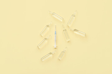 Empty syringe and ampoules with medicine on beige background