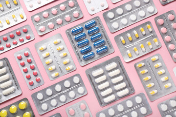 Blister packs with different pills on pink background