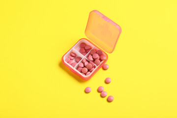 Container with pills on yellow background