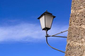 Background with wall-mounted street lamp during daytime on blue sky