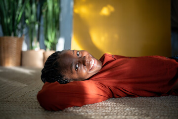 Carefree relaxed african american woman rest on carpet looking at camera smiling. Portrait serene...