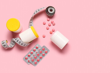 Bottles, blister packs with weight loss pills and measuring tape on pink background