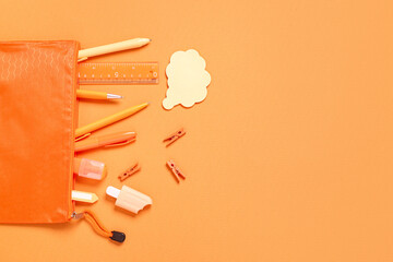 Pencil case with different school stationery on orange background