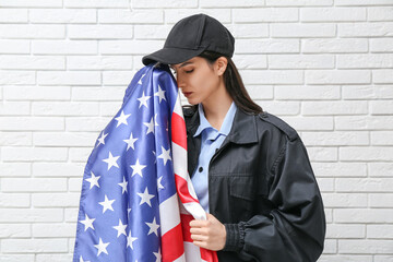 Female police officer with USA flag on white brick background