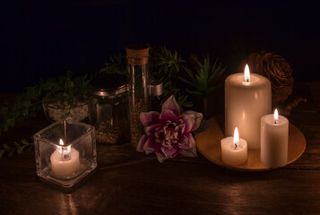 lit candles and decorative objects with plants, herbs, flowers in a dark environment