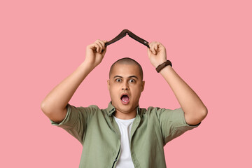 Surprised young man with empty wallet on pink background