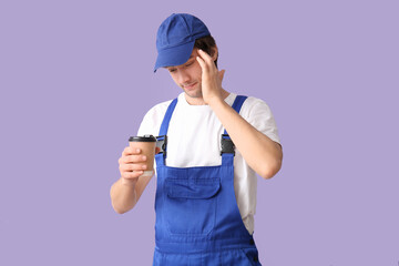Tired male worker with coffee cup on lilac background